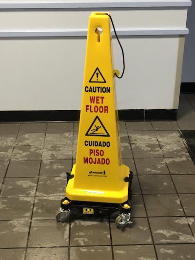 yellow caution sign on wet tile floor